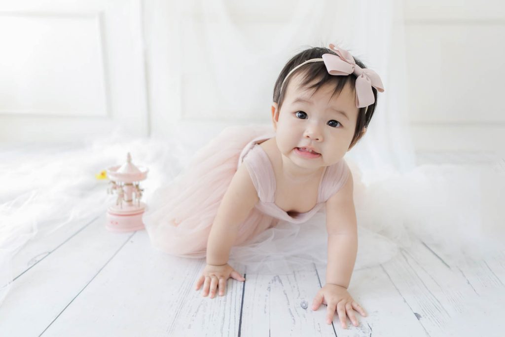 Baby girl first wearing a pink dress crawling on the floor