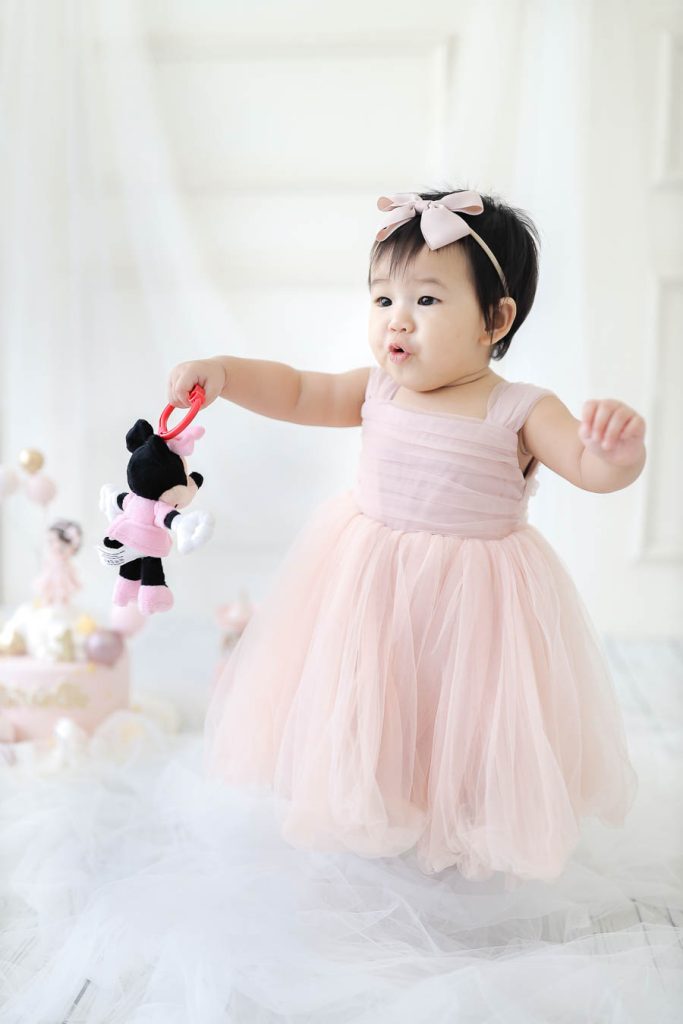 baby girl with pink dress outfit photostudio at her first birthday cake