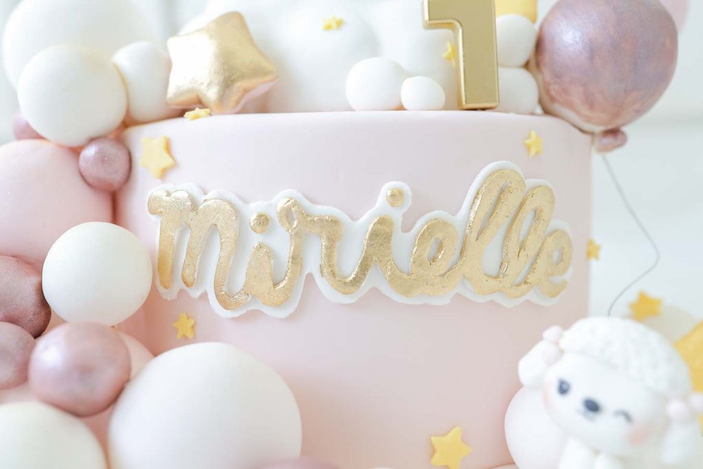 Close-up of pastel balloon birthday decoration with “One” sign for a baby girl.